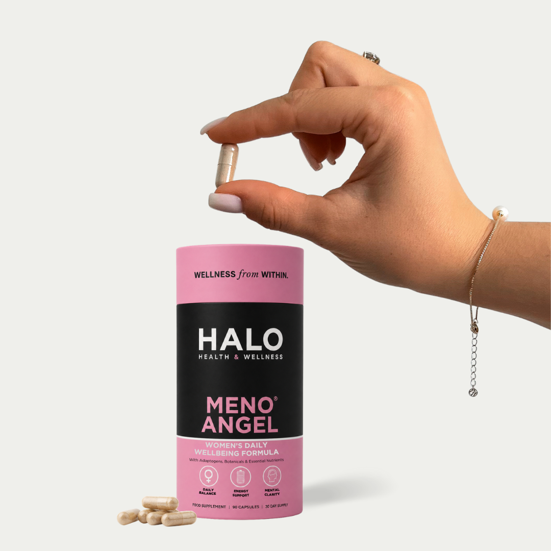 Hand holding a pill above a Halo Meno Angel supplement container on a white background