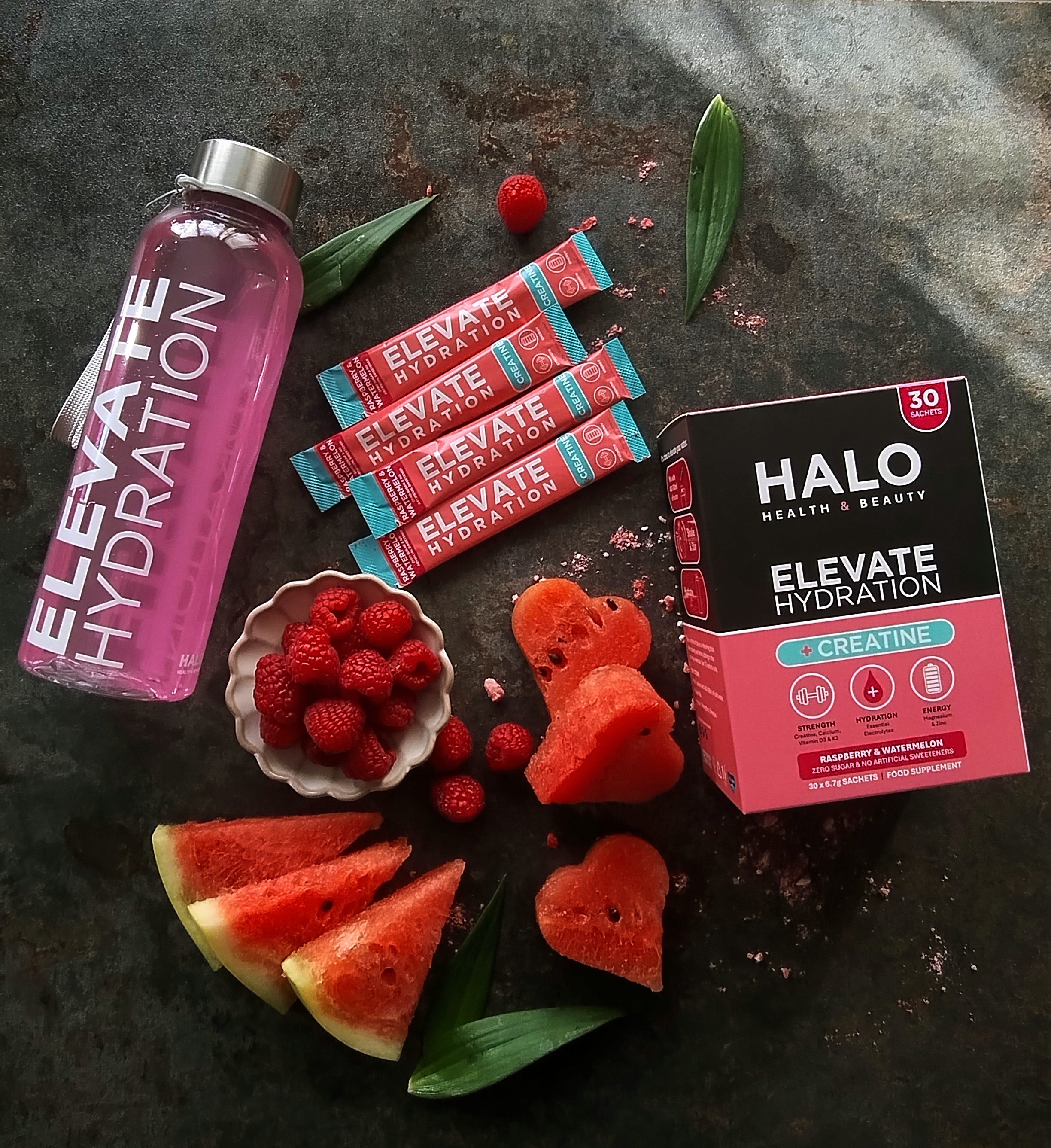 Elevate Hydration bottle, packets, and Halo Health & Beauty Elevate Hydration +Creatine pack with watermelon and raspberries. Photo Credit Malgorzara Wojas.